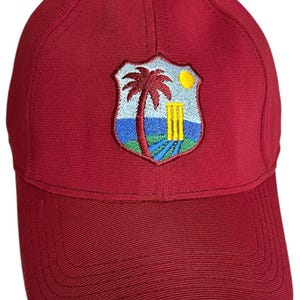 May include: Maroon baseball cap featuring an embroidered crest with a palm tree, sun, and cricket wickets. The cap has a curved brim and a structured crown. The crest is in shades of blue, yellow, and green.