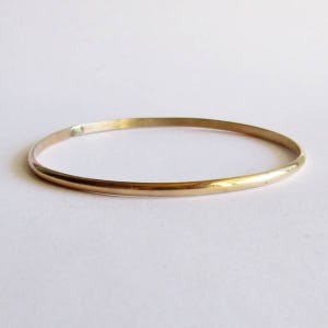 Puede incluir: Un brazalete de oro simple. El brazalete es delgado y tiene un acabado liso y pulido.