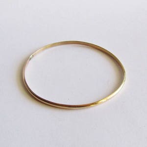Puede incluir: Un brazalete de oro simple. El brazalete es delgado y tiene un acabado liso y pulido.