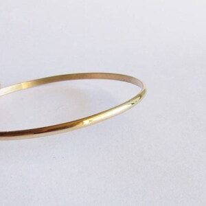 Puede incluir: Un brazalete de oro simple. El brazalete es delgado y tiene un acabado liso y pulido.