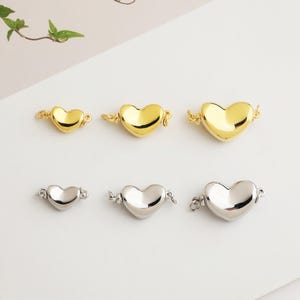 Peut inclure: Six fermoirs de bijoux en forme de cœur, en or et en argent. Les fermoirs dorés sont en trois tailles, et les fermoirs argentés sont en trois tailles. Chaque fermoir a une boucle de chaque côté pour la fixation.