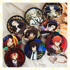 May include: A collection of round, colorful anime character buttons. Each button features a different character with unique hairstyles and outfits. Some buttons have character names like "Osamu Dazai" and "Asushi Nakajima".