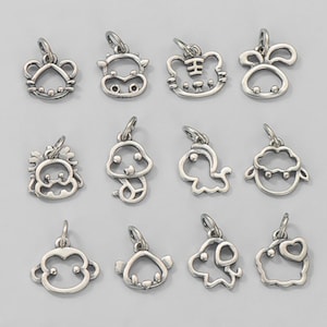 May include: A collection of twelve silver-toned animal charm pendants, each with a loop for attaching to a chain or bracelet. The charms depict various animals, including a mouse, cow, tiger, rabbit, monkey, and sheep.