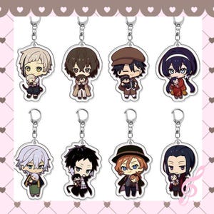 Peut inclure: Huit porte-clés de personnages de style anime avec des anneaux argentés. Chaque porte-clés présente un design de personnage différent, avec des couleurs de cheveux et des tenues variées. Les personnages tiennent de petites figurines. Le fond est rose clair avec une bordure décorative.