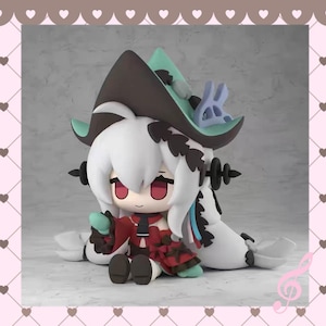 May include: A detailed figurine of a character with white hair, red eyes, and a red and black dress. The figure wears a hat with a teal brim and a small purple bunny. The figure is sitting down with a teal object in its hands.
