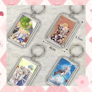 May include: Four rectangular keychains with anime-style illustrations. Each keychain is 4 cm wide and 5.7 cm tall. The keychains feature different colorful images of characters. The keychains have silver-colored key rings.