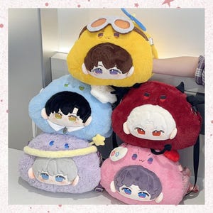 May include: Five plush backpacks in a stack, each a different colour: yellow, blue, red, purple, and pink. Each backpack has a cartoon face and a character-themed hat. The yellow backpack has goggles and a propeller.