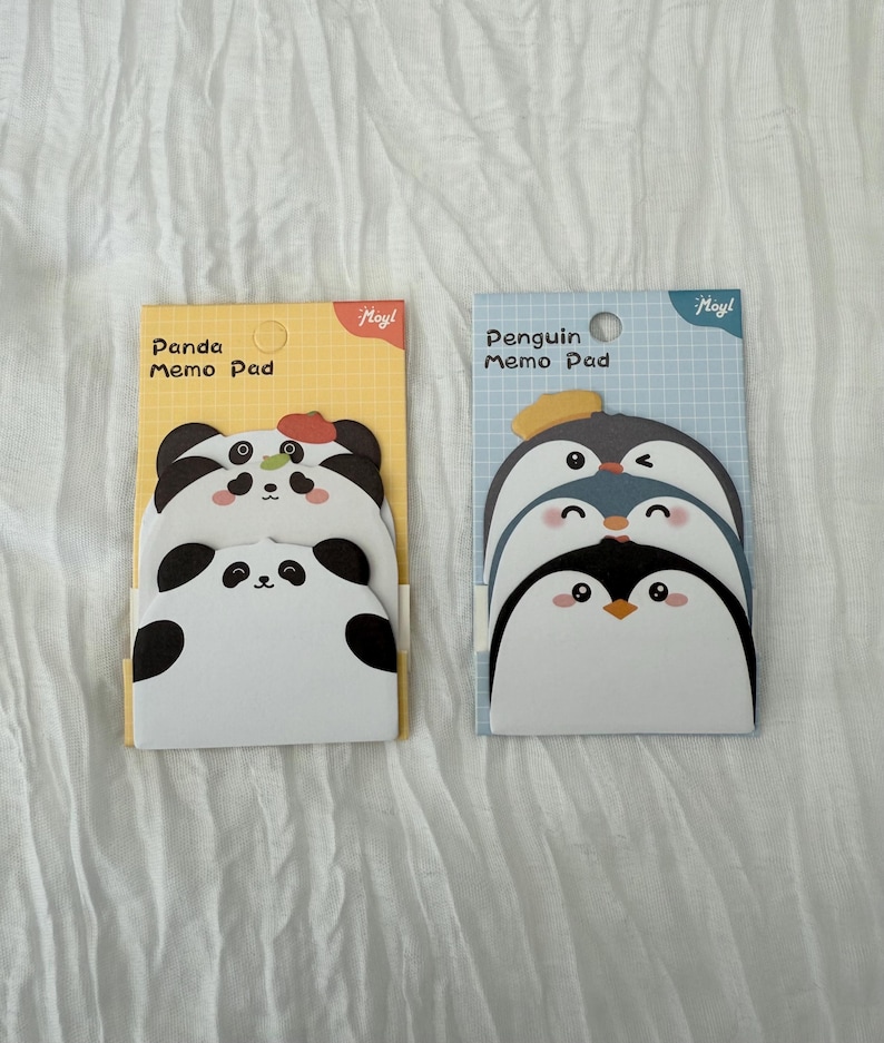 K&ouml;nnte beinhalten: Zwei Notizbl&ouml;cke mit Tiermotiven. Ein Block hat ein Panda-Design mit dem Text "Panda Memo Pad" auf gelbem Hintergrund. Der andere hat ein Pinguin-Design mit dem Text "Penguin Memo Pad" auf blauem Hintergrund.