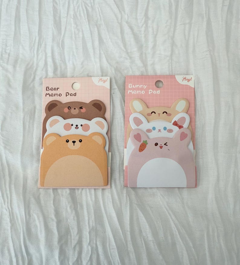 K&ouml;nnte beinhalten: Zwei Notizblock-Sets mit niedlichen Tierdesigns. Ein Set hat b&auml;renf&ouml;rmige Bl&ouml;cke in Braun und Beige, beschriftet mit "Bear Memo Pad". Das andere Set hat hasenf&ouml;rmige Bl&ouml;cke in Rosa und Beige, beschriftet mit "Bunny Memo Pad".