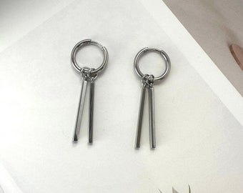 May include: A pair of silver hoop earrings with two dangling rectangular bars.