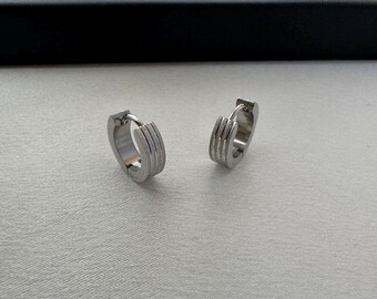 Puede incluir: Un par de pendientes de aro de plata con un diseño acanalado.