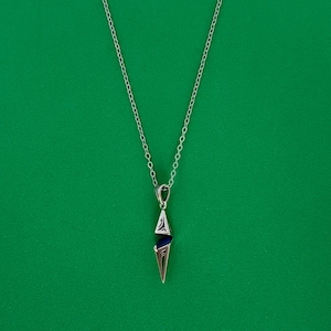 May include: A silver necklace with a geometric pendant featuring a blue gemstone. The pendant is shaped like a sharp point.
