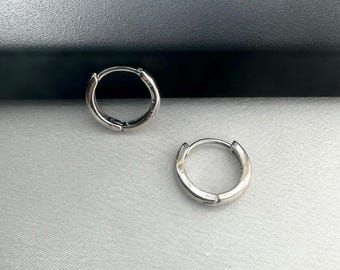 Puede incluir: Dos pendientes de aro de plata. Los pendientes son simples y minimalistas en diseño.