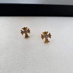 May include: A pair of gold cross earrings with clear rhinestones.