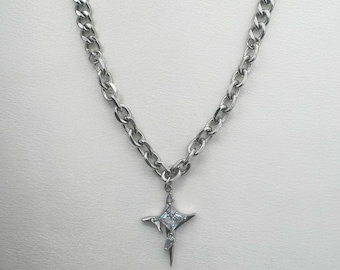Può includere: Una collana con catena d'argento con un ciondolo a forma di stella con un cristallo trasparente al centro.