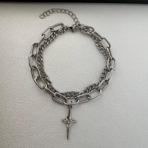 Puede incluir: Un collar de cadena de plata con dos estilos de cadena diferentes, uno más grueso y otro más fino, con un colgante de estrella de plata.