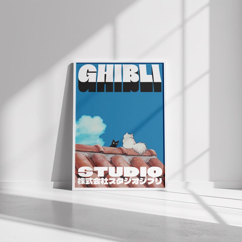 May include: A blue and white poster with the text "GHIBLI" in black letters and "STUDIO" in white letters. The poster also features a black cat and a white cat sitting on a red tiled roof.