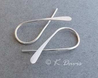 May include: A pair of silver earrings with a simple, curved design. The earrings are made of thin wire and have a smooth, polished finish.