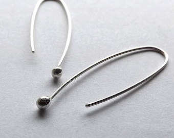 May include: A pair of silver hoop earrings with a small ball at the end of each hoop.