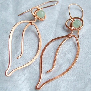 Puede incluir: Un par de pendientes de alambre de cobre con una piedra preciosa verde claro en cada uno. Los pendientes tienen forma de l&aacute;grima con un delicado dise&ntilde;o de alambre.