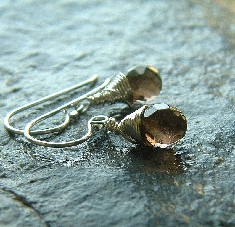 May include: A pair of silver wire wrapped earrings with brown faceted gemstone drops.