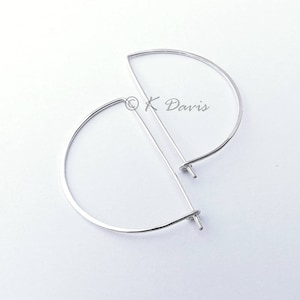 May include: A pair of silver half-circle earrings with a straight bar connecting the ends of the half-circles.