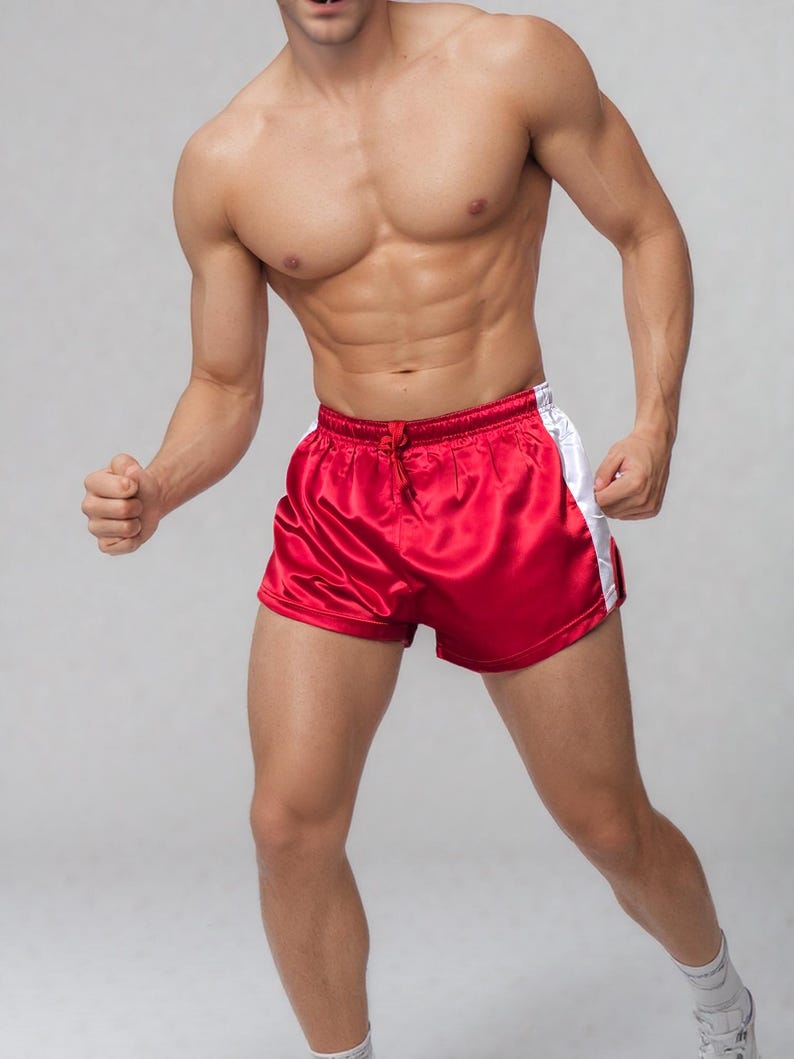 May include: Red satin athletic shorts with white side stripes. The shorts have a drawstring waist and a shiny finish. The shorts are designed for athletic activities and are a vibrant red color.