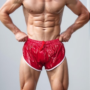 Puede incluir: Pantalones cortos deportivos rojos con ribete blanco y cintura con cordón. El material brillante crea un efecto brillante. Estos pantalones cortos están diseñados para deportes y son de un color vibrante. Miden unos 30 cm de largo.
