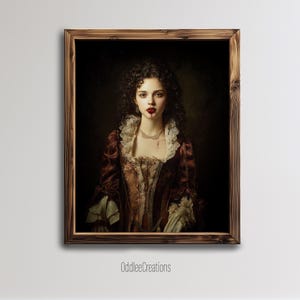 May include: A framed portrait of a woman with dark curly hair, wearing a burgundy and cream-coloured dress with a lace collar. The woman has red lipstick and a small amount of blood on her chin and neck. The frame is made of dark wood. The text "OddleeCreations" is at the bottom.