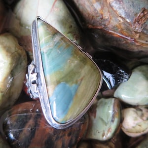 Puede incluir: Un anillo de plata con una piedra preciosa triangular verde, azul y blanca engastada en un engaste de plata.