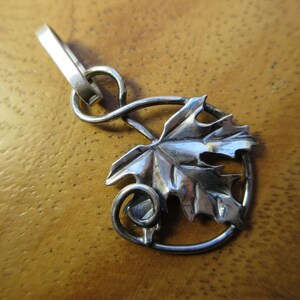 Peut inclure: Un pendentif en argent avec un motif de feuille d'&eacute;rable d&eacute;taill&eacute; et une vigne enroul&eacute;e. Le pendentif a une boucle en haut pour l'attacher &agrave; une cha&icirc;ne.