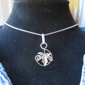 Peut inclure: Un collier en argent avec une cha&icirc;ne d&eacute;licate et un pendentif en forme de feuille stylis&eacute;e.