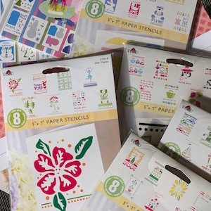 May include: A collection of paper stencils for card making. The stencils are in various designs, including flowers, baby-themed images, and holiday motifs. Each package contains 8 stencils, measuring 5" x 7". The packages are in clear plastic with a cardboard backing.