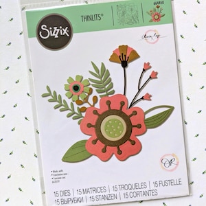 May include: A Sizzix Thinlits 664450 die set by Olivia Rose in original packaging. The package displays a floral arrangement made of 15 paper-cut shapes in shades of coral, olive green, and brown, featuring various flower and leaf designs.