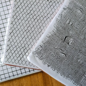 May include: Three white paper sheets with black grid and net patterns. The sheets are in a clear plastic sleeve. The patterns include a grid, a chain-link fence design, and a distressed net.