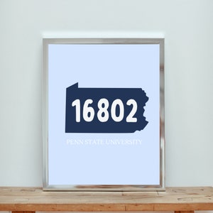 Puede incluir: Una impresión enmarcada con una silueta azul del estado de Pensilvania y el número 16802 en texto blanco. El texto "Penn State University" está debajo de la silueta.