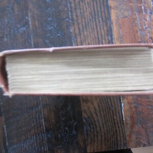 Puede incluir: Un libro de tapa dura marr&oacute;n con lomo blanco y una cubierta texturizada.