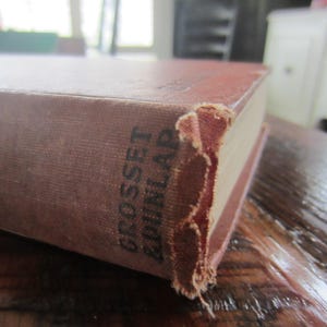 Puede incluir: Primer plano de un libro marr&oacute;n con el texto "Grosset & Dunlap" impreso en el lomo.
