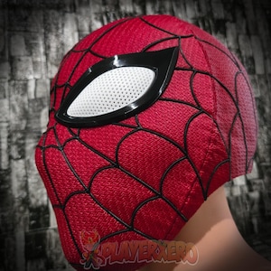 Pode incluir: Uma máscara vermelha do Homem-Aranha com teias pretas e grandes lentes oculares brancas contornadas em preto. A máscara é feita de um tecido texturizado e foi projetada para cobrir toda a cabeça.