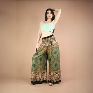 May include: Green wide-leg pants with a gold and brown mandala print. The pants have an elastic waistband and a relaxed fit.