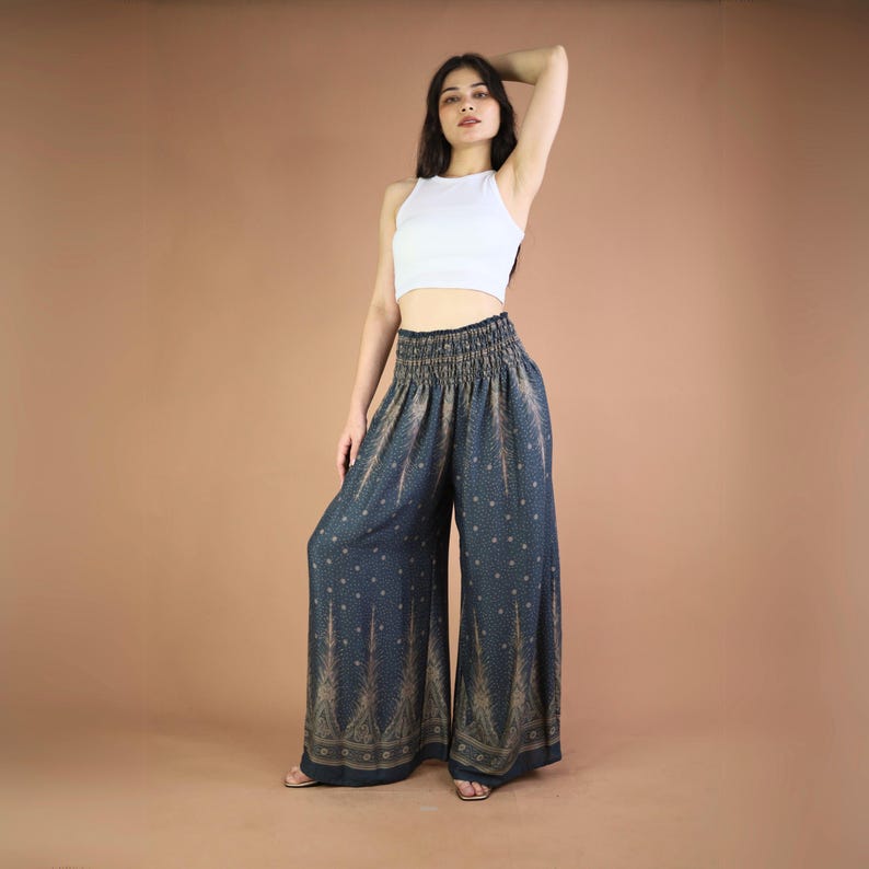 May include: A woman wearing a white crop top and wide-legged pants with a blue and gold print. The pants have an elastic waistband and a flowing silhouette.