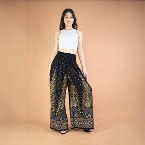 May include: Black wide-leg pants with a peacock feather print in gold and blue. The pants have an elastic waistband and a relaxed fit.