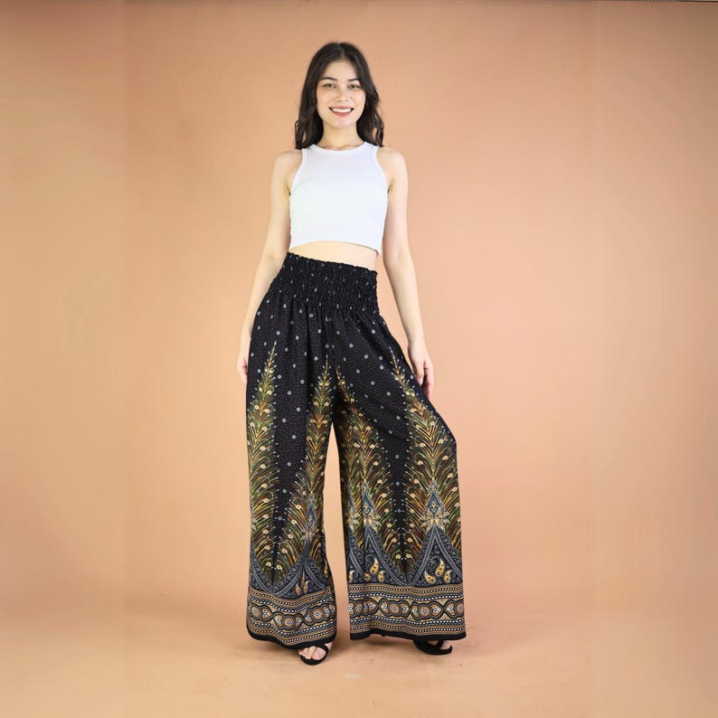 May include: Black wide-leg pants with a peacock feather print in gold and blue. The pants have an elastic waistband and a relaxed fit.
