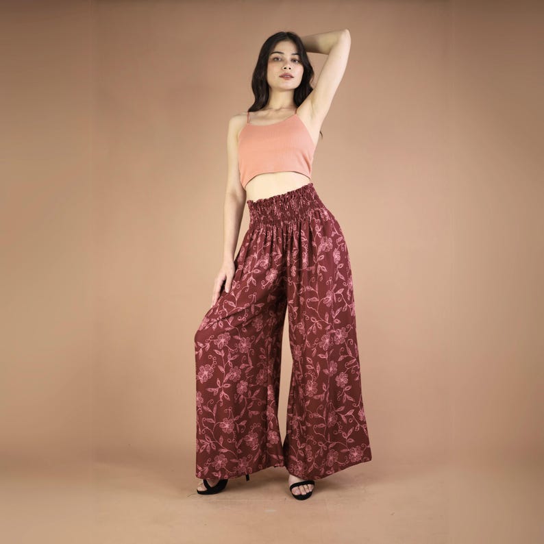 May include: A woman wearing a pink tank top and wide-legged pants with a floral print. The pants have an elastic waistband and a loose, flowing fit.