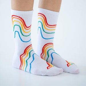 May include: White socks with a rainbow design. The socks have five stripes of red, orange, yellow, green, and blue.