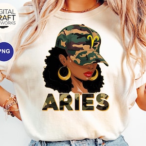 Könnte beinhalten: Ein weißes T-Shirt mit einem Aufdruck einer Frau mit braunen Haaren, die eine Baseballkappe im Tarnmuster trägt. Unter dem Aufdruck steht das Wort "Aries" in Tarnmusterbuchstaben.