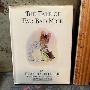 May include: A vintage book cover featuring a cartoon illustration of a mouse holding a broom. The title of the book is "The Tale of Two Bad Mice" by Beatrix Potter. The book is published by F. Warne & Co.