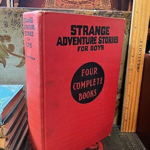 May include: A red hardcover book titled "Strange Adventure Stories for Boys" with a black circle on the cover that says "Four Complete Books".