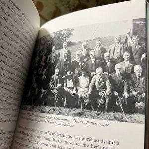 May include: A black and white photograph of the 1922 Hawkshead Show Committee, with Beatrix Potter at the center. The group of men and women are posed outdoors, some seated and others standing. The image is from a book.