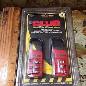 May include: Two red and black The Club tool box locks in a clear plastic package. The locks have combination dials and the text "The Club Automotive Security Series" is visible. The package also states "Lifetime Guarantee".
